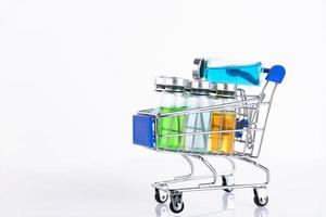 Glass vials of different colors for the vaccine in the shopping cart on a white background. Copy space. Selective focus. photo