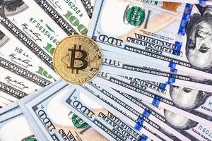 Golden bitcoin on hundred dollar bills background photo