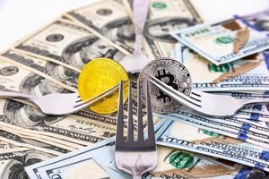 Platinum and gold bitcoin on a background of one hundred dollar bills and cutlery. photo