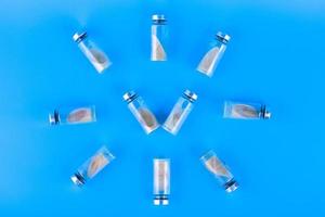 Vials, ampoules with a dry probiotic, bifidobacteria inside on a blue background are laid out in the form of a clock. Copy space. photo