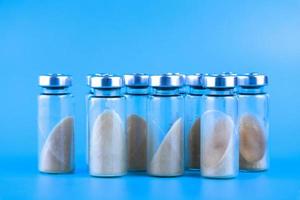 Vials, ampoules with dry probiotic, bifidobacteria, with probiotic powder inside on a blue background. Copy space. photo