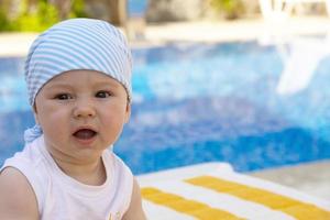 A handsome, little boy sits on a sun lounger by the pool. Selective focus. photo