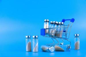 Vials, ampoules with dry probiotic, bifidobacteria, with probiotic powder inside, on a trolley in a supermarket. on a blue background. Copy space. photo