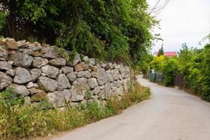 Fragment of the old stone wall of the fence of the house. View from the street. photo