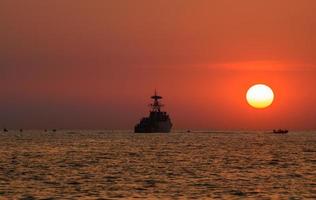 Silhouette military war ship and the sun. photo