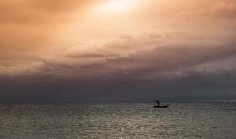 Silhouette fishery boats in the sea with sunset lighting. photo