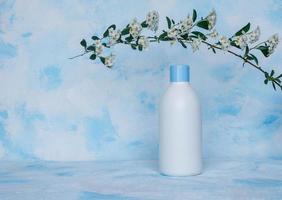 Pure white, plastic, container. Packaging, bottle template for cosmetics, cream, hair mask, for medical and beauty products. Light background with a flowering branch on top photo