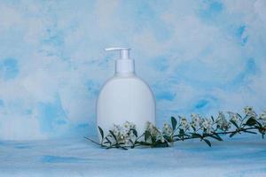 Pure white, plastic, container. Packaging, bottle template for cosmetics, cream, hair mask, for medical and beauty products. Light background with a flowering branch on top photo