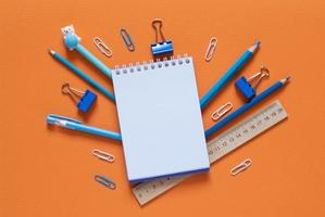 Back to school concept. School and office supplies on the office table. Orange background.Flat lay photo