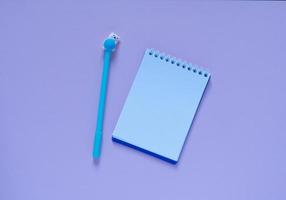 Back to school concept.Notepad and blue pen on a pink background. View from above..Flat lay photo