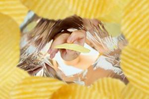 Hand hold potato chips inside snack foil bag photo