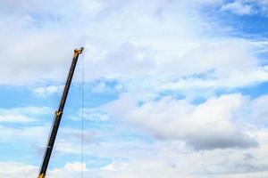 brazos telescópicos de camión grúa de construcción móvil con nubes y cielo azul foto