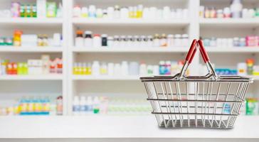 Empty shopping basket on pharmacy drugstore counter with blur shelves of medicine and vitamin supplements background photo