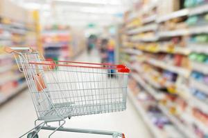 Supermarket aisle with empty shopping cart at grocery store retail business concept photo