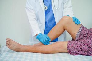 Doctor checking Asian elderly woman patient with scar knee replacement surgery in hospital. photo