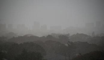 lluvia intensa de fondo que cae del cielo de la temporada de lluvias, silueta de árboles y edificios, tailandia tropical. foto