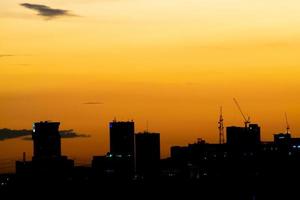 da una sensación cálida, la puesta de sol detrás del edificio de la ciudad, los edificios altos de la ciudad de la silueta, la silueta del edificio de nuevo el hermoso fondo del cielo y el concepto de libertad. foto