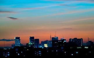 da una sensación cálida, la puesta de sol detrás del edificio de la ciudad, los edificios altos de la ciudad de la silueta, la silueta del edificio de nuevo el hermoso fondo del cielo y el concepto de libertad. foto