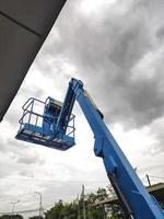 Manlift crane with platform lifting to the roof top of a building photo