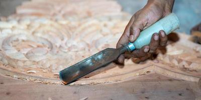 close-up carpenter man's hand treats the tree, cuts the shavings. Copy space. woody curl. Manual processing of wood in the workshop. joiner woodworker in process. photo