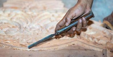 close-up carpenter man's hand treats the tree, cuts the shavings. Copy space. woody curl. Manual processing of wood in the workshop. joiner woodworker in process. photo