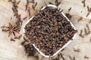 spices of cloves scattered on an old wooden table photo