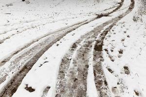 traces of the wheels of the car on a rural road covered with snow photo
