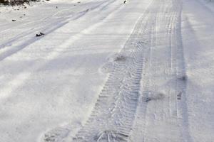 traces of the wheels of the car on the snow covered road photo