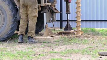 une équipe de travailleurs avec une plate-forme de forage sur voiture fore un puits artésien pour l'eau dans le sol. insertion d'un tubage métallique dans le sol, installation d'un abreuvoir individuel video