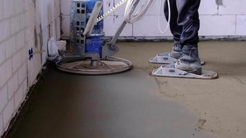 Ramming and grinding of semi-dry floor screed by a machine with a rotating disk for leveling. Construction of a concrete floor in the house, a master with special equipment. Slow motion video