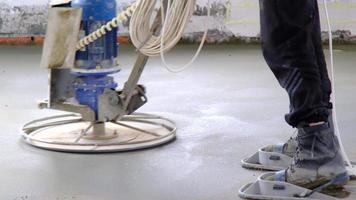 Ramming and grinding of semi-dry floor screed by a machine with a rotating disk for leveling. Construction of a concrete floor in the house, a master with special equipment. Slow motion video