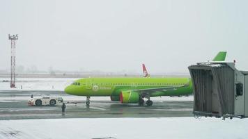 NOVOSIBIRSK, RUSSIAN FEDERATION November 15, 2020 - S7 Airlines Airbus A320 with covered engines being towed by tug truck for maintenace. video