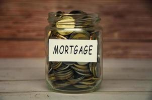 Mortgage label on coin jar on top of wooden desk with blurred background. photo