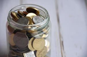 Close up of coins in a jar on wooden table with customizable space for text or ideas. Copy space photo