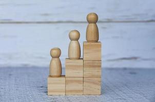 Wooden people figures on top of wooden blocks. Career growth concept photo