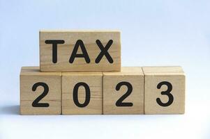 Tax 2023 text on wooden blocks with white background. photo