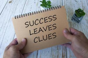 Success leaves clues text written on brown notepad. Motivational concept. photo