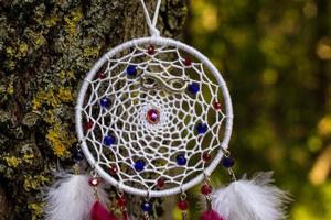 atrapasueños hecho a mano con hilos de plumas y cuerda de cuentas colgando foto