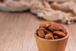 almendras saladas en una taza de madera. concepto de comida saludable, vista superior. foto