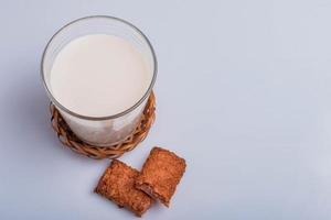 Barra de cereales y leche fresca sobre fondo blanco. foto