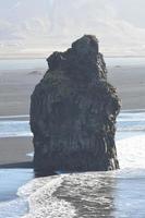 Large rock standing on the beach off the coast of Vik photo