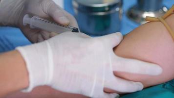 technicien de laboratoire tenant un échantillon de tube de sang pour étude, piquant une seringue à aiguille dans le bras du patient prélevant un échantillon de sang pour un test sanguin.