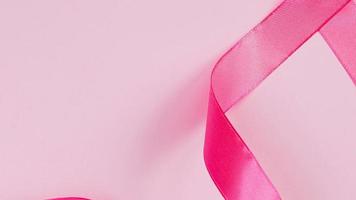 cinta rosa sobre fondo de color. símbolo del mes de concientización sobre el cáncer de mama. concepto de atención médica para mujeres. video