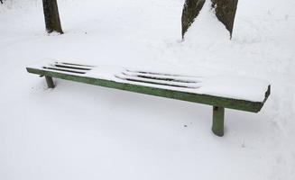 antiguo banco de madera cubierto de nieve foto