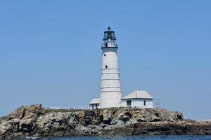 faro en una cornisa de roca en el puerto de boston foto