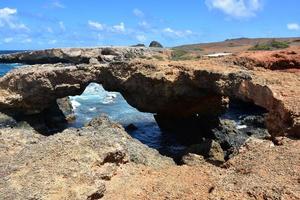 puente natural de aruba en la playa de arena negra foto