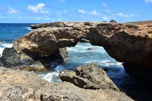 puente natural de roca de lava en la costa de aruba foto