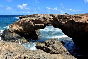 puente natural de roca de lava en la playa de arena negra foto