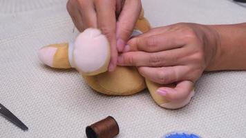 Woman sewing by hand, closeup. Mother sews up a torn doll for her little daughter by hand. video
