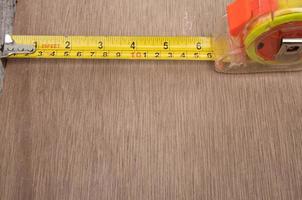 Photo of a yellow meter measuring device isolated on a background on a wooden board